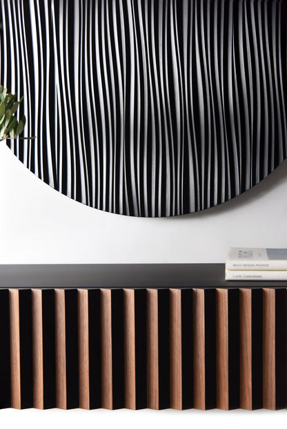 Close up of the round black wall sculpture relief above the walnut and black console