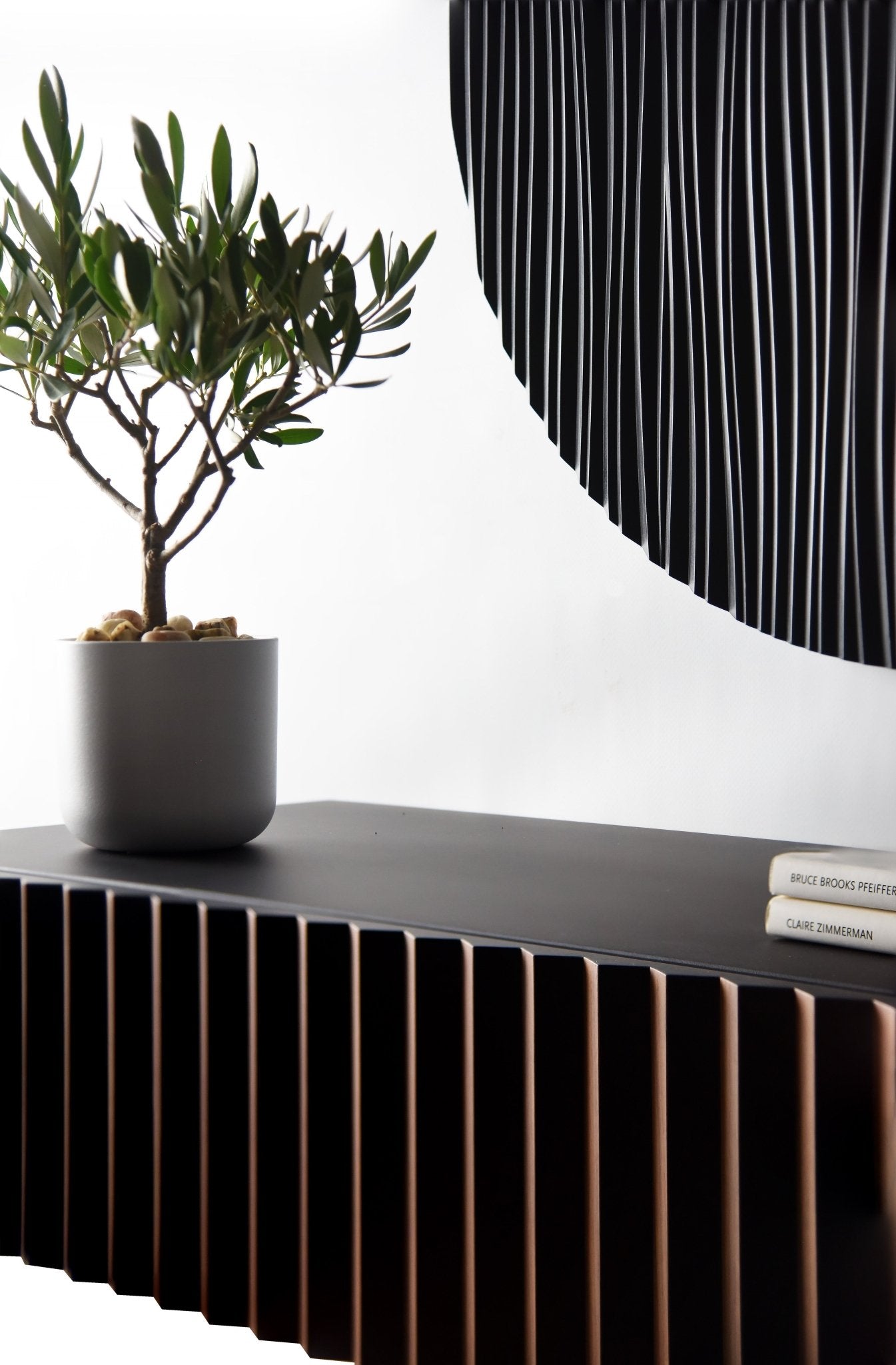 Angled interior detail of the walnut and black suspended console with sculpture partially visible