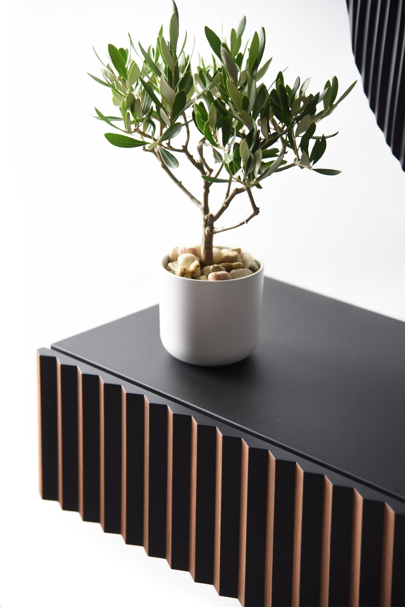 Close up of the console top and walnut and black front detail with a plant
