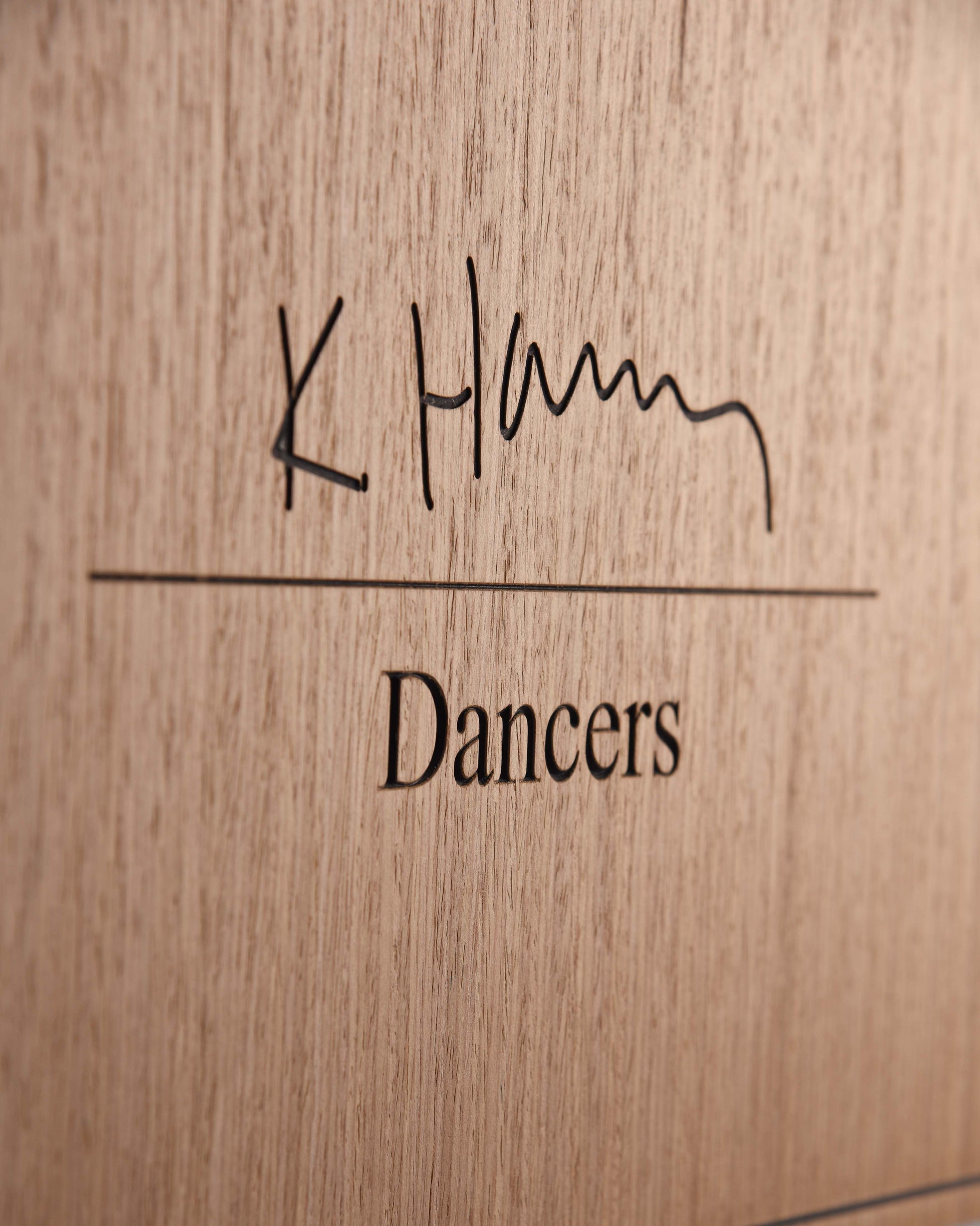 Macro detail of engraved title and wood grain on The Dancers panel
