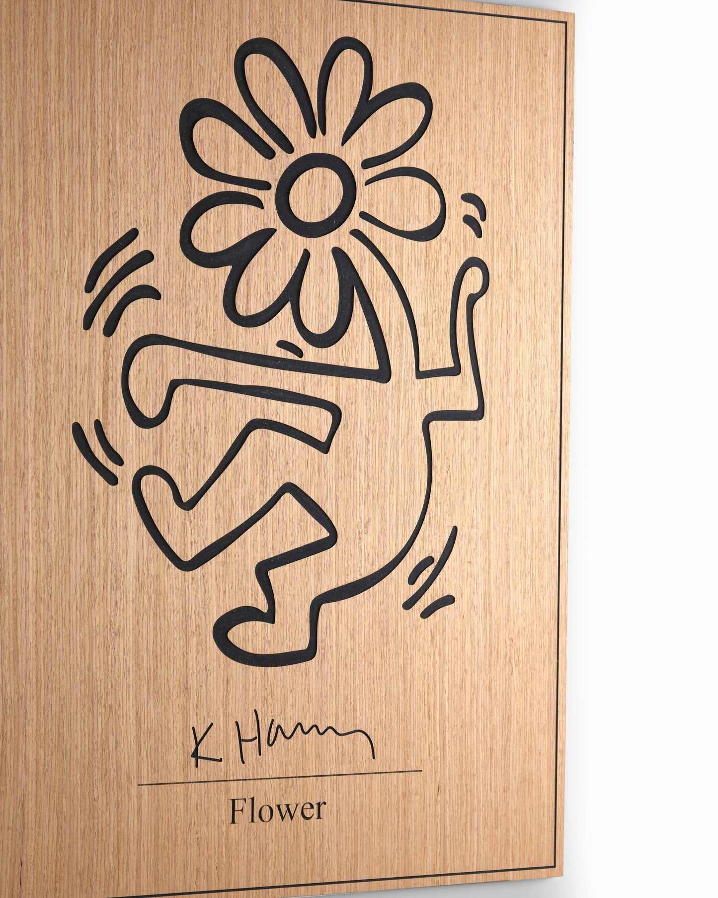 Angled detail of The Flower panel showing carved relief depth on oak and black