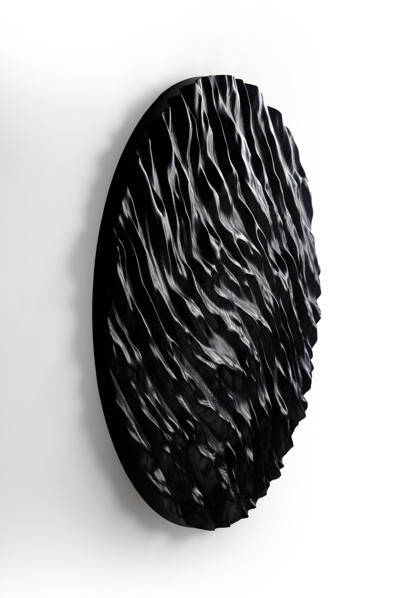 Dramatic shadows highlight wave carvings, linking boho chic interior themes with minimal house design for a unique wall statement.