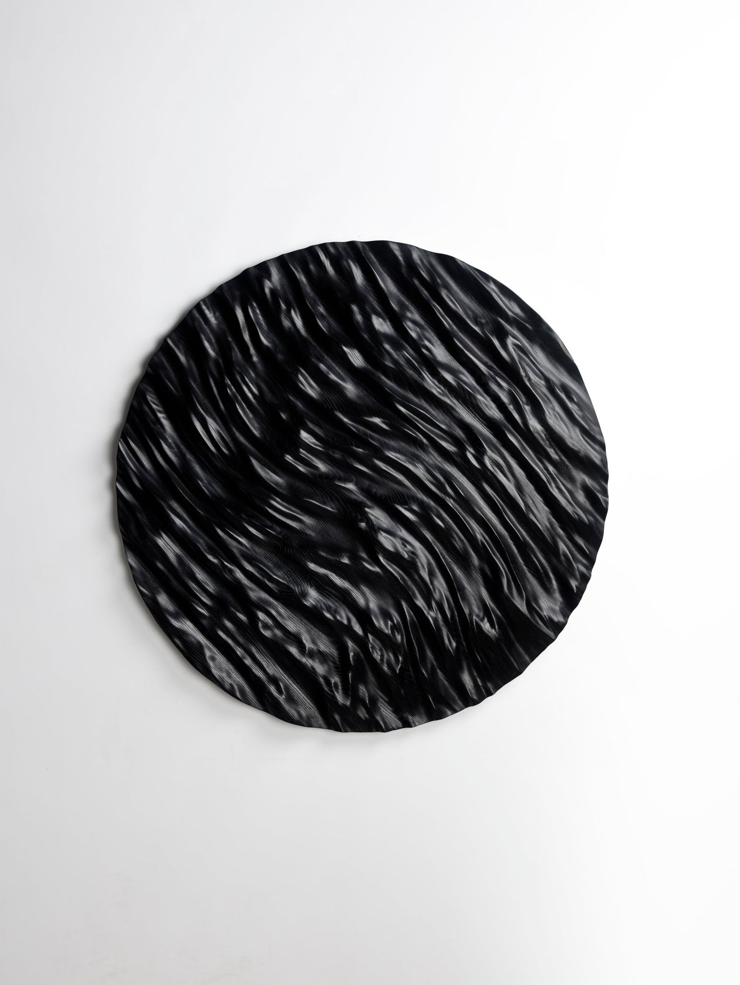 Curved grooves capturing an ocean swirl effect in black wood, uniting hallway decor ideas and geometry art in a striking focal piece.