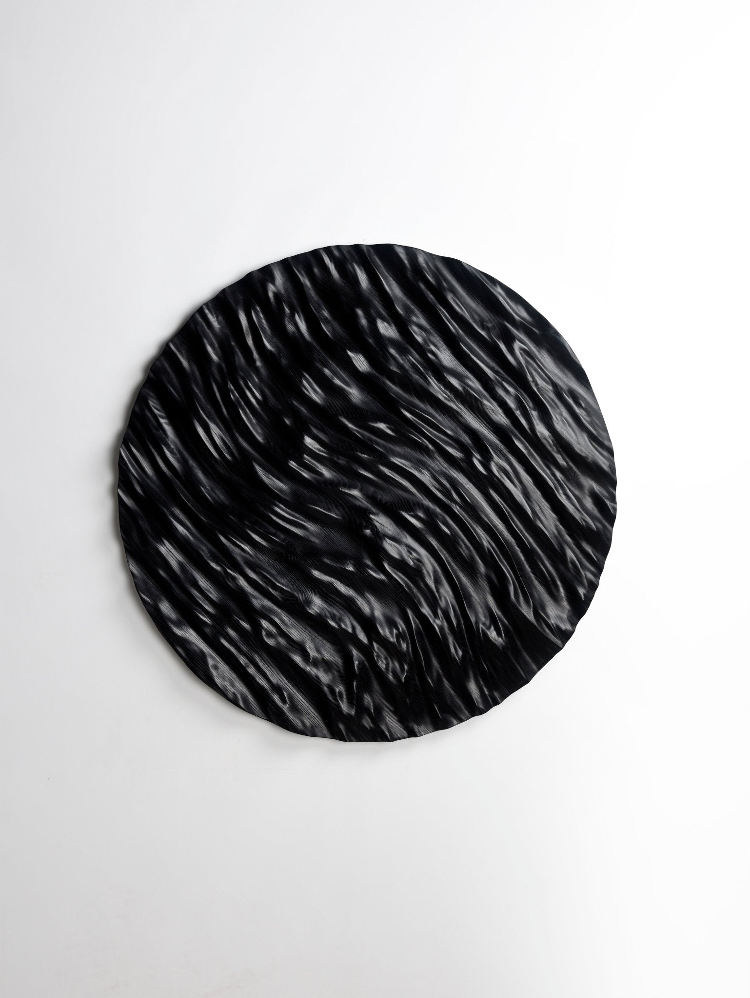 Curved grooves capturing an ocean swirl effect in black wood, uniting hallway decor ideas and geometry art in a striking focal piece.