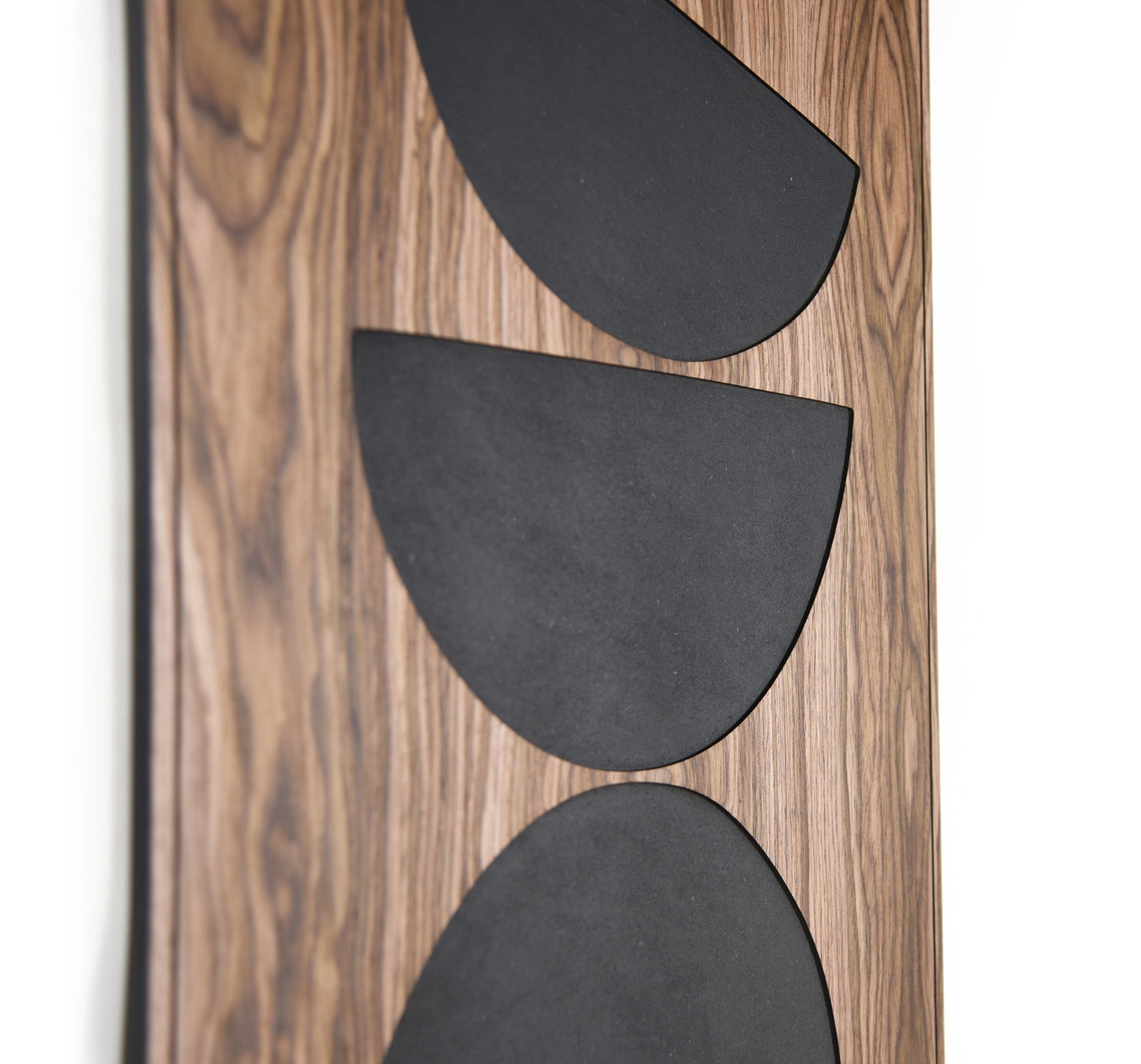 Close up of stacked black shapes on walnut, relief depth and grain detail