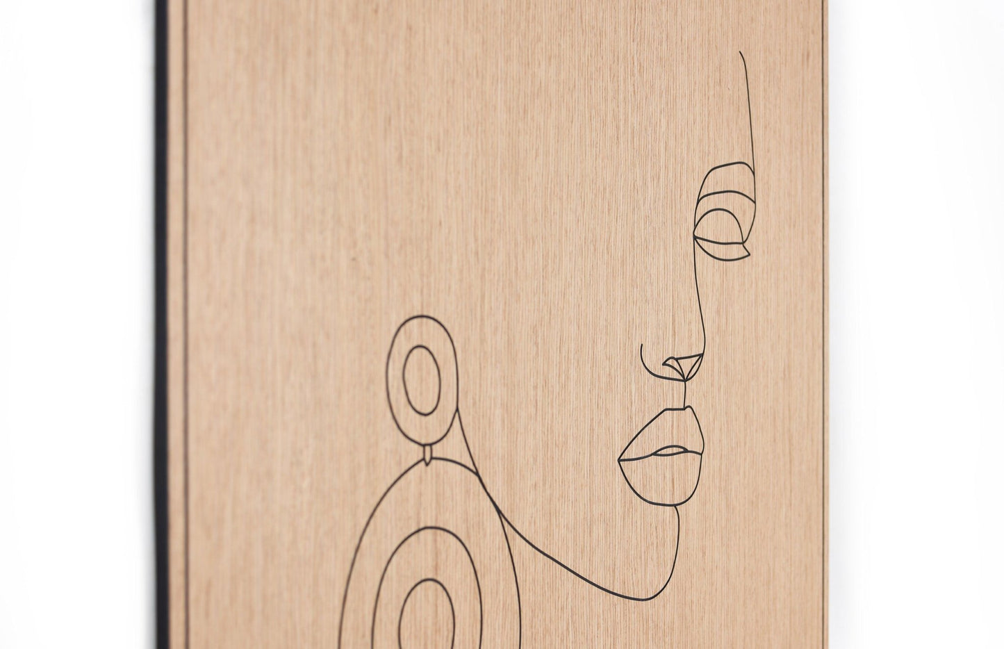 Angled view of the carved line portrait on oak highlighting depth and surface texture