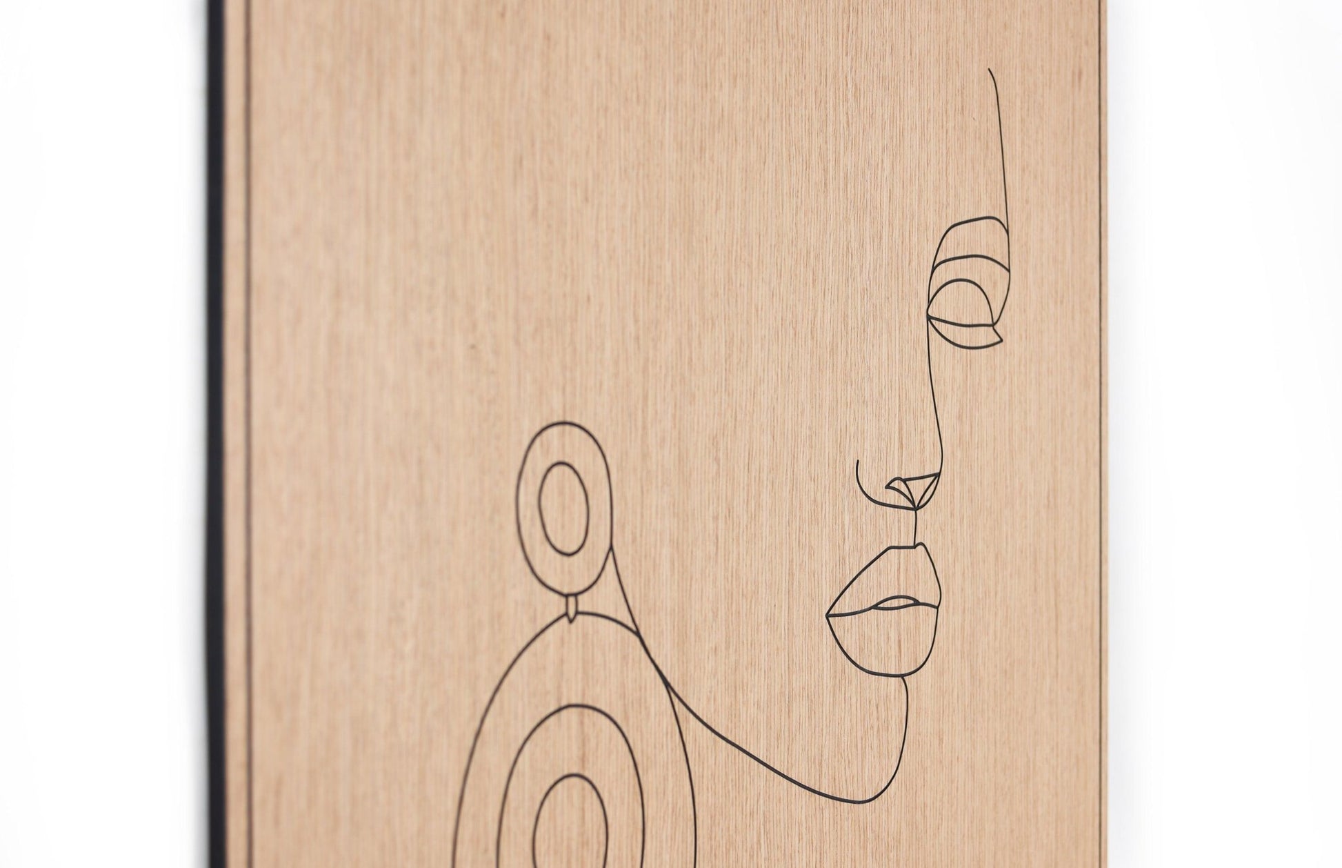 Angled view of the carved line portrait on oak highlighting depth and surface texture